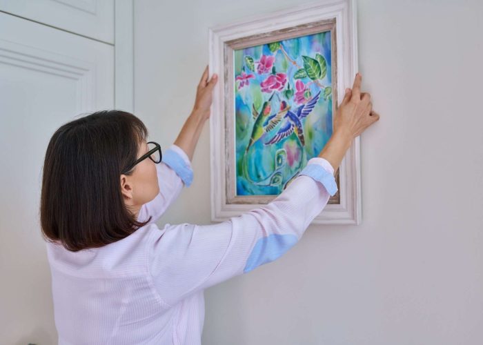 Woman hanging floral birds art framed at home on the wall